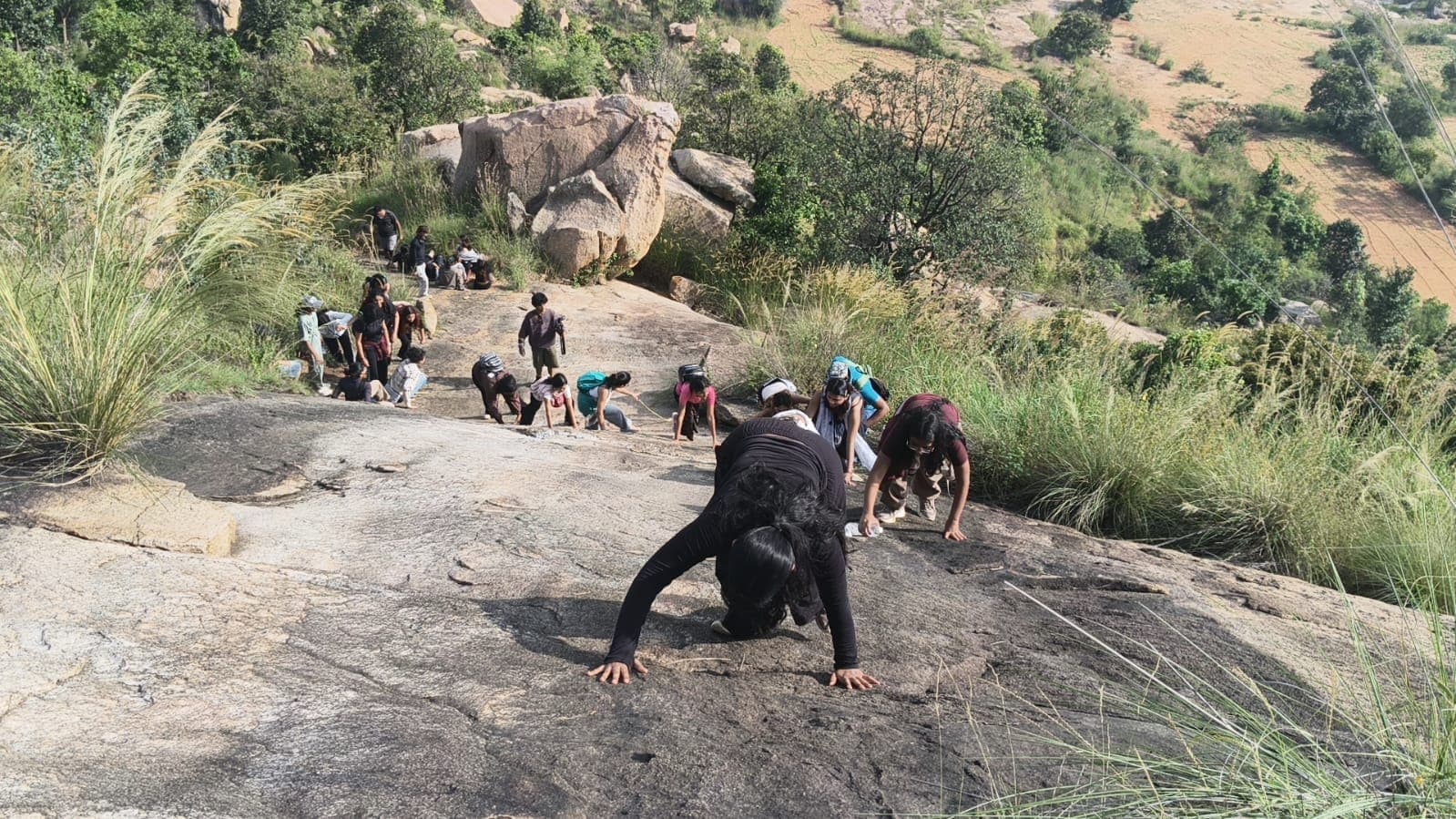 Trekkers scrambling and climbing up steep natural granite rock faces