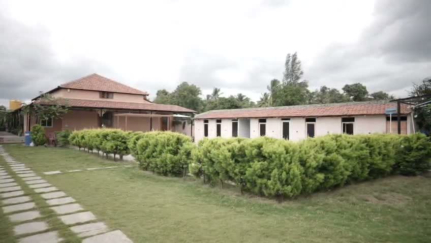 Cinematic camera sweep across green lawns, stone pathways, and cottage accommodations at Shree Adventure